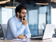 Alphabet Stock Soars Why I’m Holding An investor sitting at a desk, thinking as they look at a laptop.