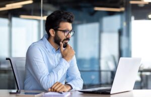 Alphabet Stock Soars Why I’m Holding An investor sitting at a desk, thinking as they look at a laptop.