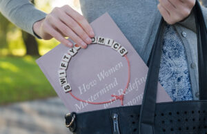 Breaking News Alert Kansas A woman's hand pulls the book "Swiftynomics" from a handbag.